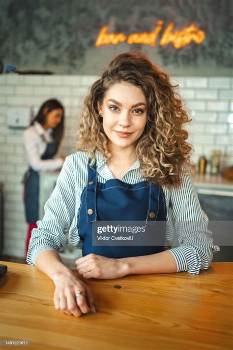 portrait of lovely waitress wearing apron and standing behind the bar