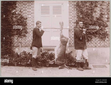 two men with a large hare on a carrying stick presumably staged part