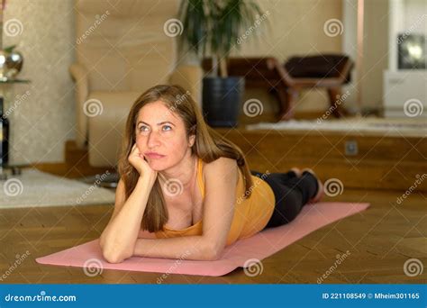 Middle Aged Woman Lying On A Yoga Mat Deep In Thought Stock Image