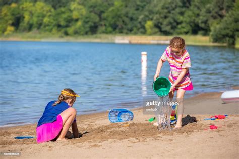 zwei junge mädchen spielen mit wasser sand am strand stock foto getty