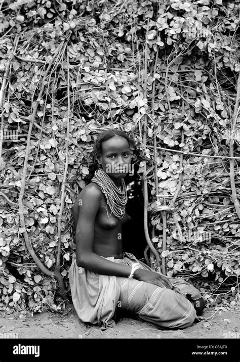 dassanech teenage girl at entrance of natural materials hut omorate