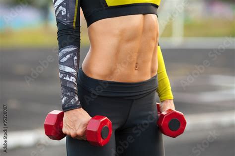 fitness woman showing abs and flat belly muscular girl with dumbbels