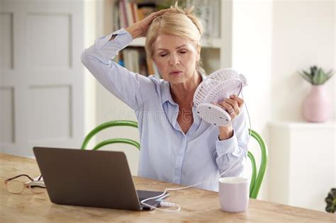 Menopausal Mature Woman Having Hot Flush At Home Cooling Herself With