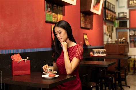 a singaporean woman in a red dress is having a local coffee by