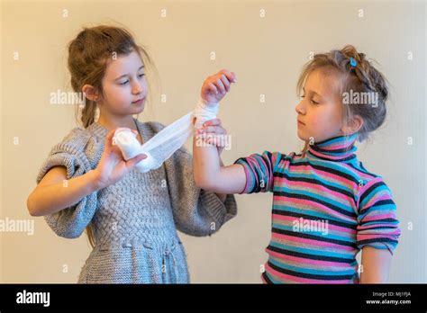 the girl bending her sister s hand two girls play doctor bandage