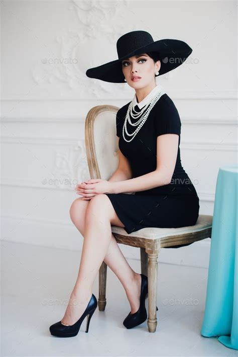Elegant Woman In Black Dress With A Hat Sitting On Chair Sitting