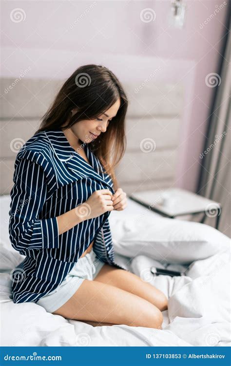 awesome girl taking off the shirl while sitting in the bed stock image