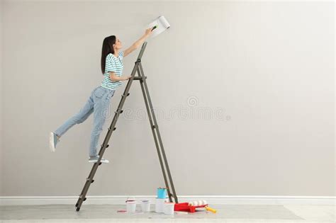 joven mujer pintando la pared con un rodillo en la escalera interior