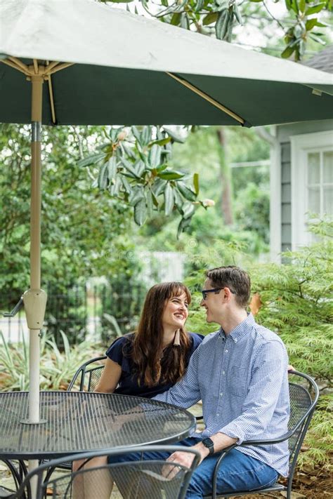 Acouple Of A Husband And Wife Sitting Under A Shaded Umbrella Patio