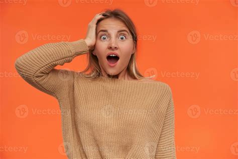 Expressive Young Open Eyed Short Haired Blonde Lady Raising Hand To Her