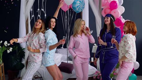 a group of dancing girls at a pajama party with glasses of champagne