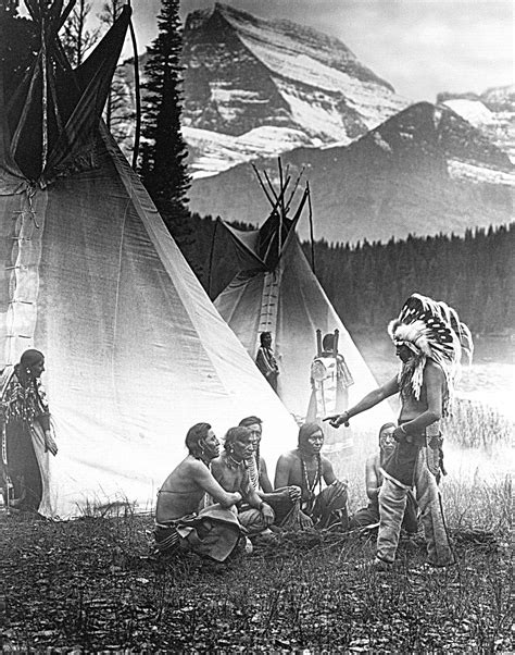 an old black and white photo of native american people in front of teepees