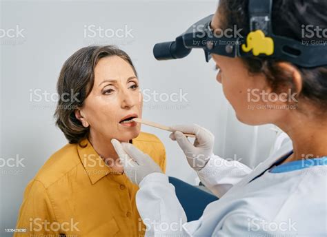 Otolaryngologist Using Inspection Spatula To Examines Mature Womans