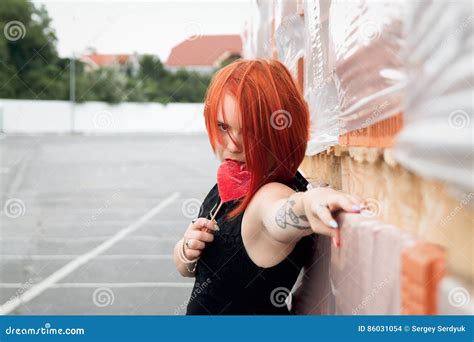 Emotional Red Haired Girl Licking Candy On A Stick And Stands A Stock