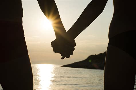 couple on a beach holding hands at sunset photograph by newnow