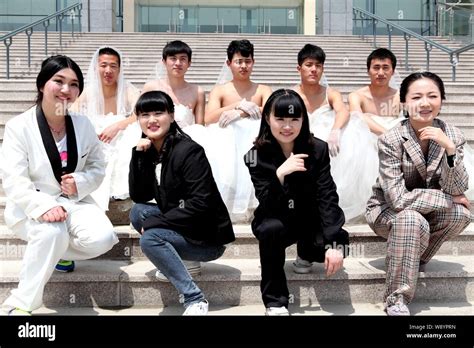male students wearing bridal wedding dresses pose   female classmates dressed  male