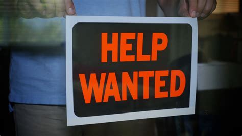 A Shop Owner Places A Help Wanted Sign In The Window