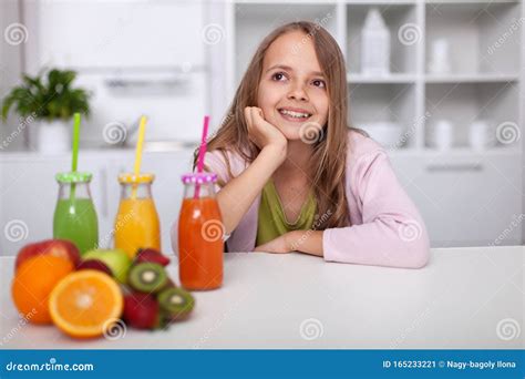 Молодая девушка подросток сидит на кухне с бутылками свежевыжатых