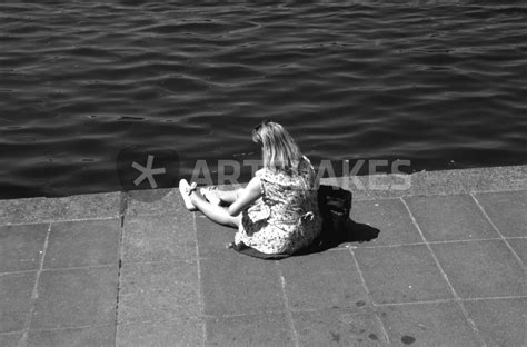 Eine Frau Sitzt In Sich Versunken Am Wasser Fotografie Als Poster
