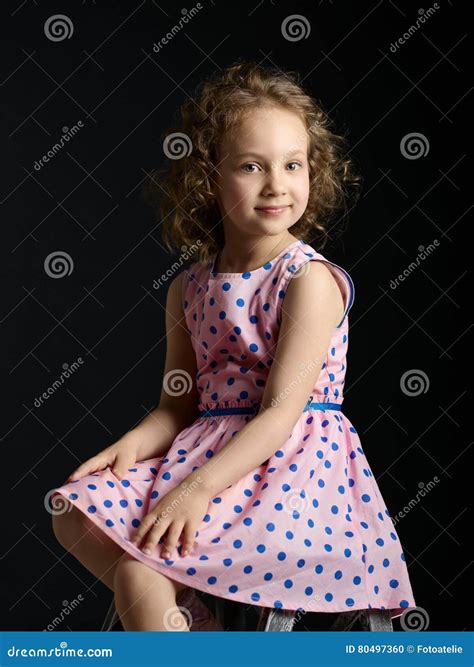 klassiek portret van een klein meisje  een roze kleding met een glimlach  stock foto image