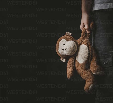 cropped image  boy holding stuffed toy  standing  black