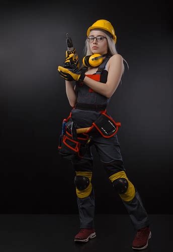 Girl In Construction Clothes And Protective Equipment Posing With A