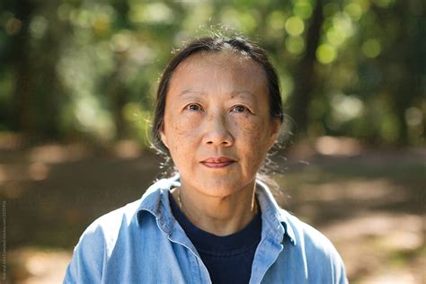 mature asian woman practicing tai chi outside by rob and julia campbell