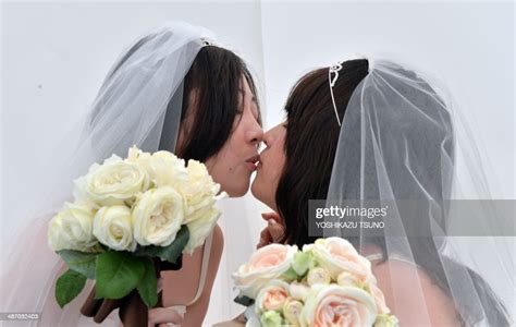 a lesbian couple kisses as they pose for photos taken by a wedding
