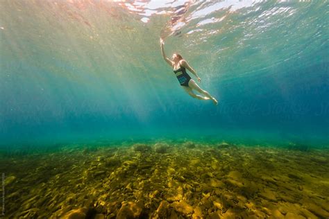 young woman swimming underwater  crystal clear summer lake  stocksy contributor jp danko