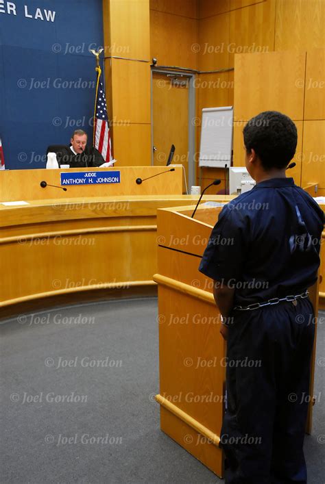 Young Offender In Court In Jumpsuit Standing Before The Judge Joel