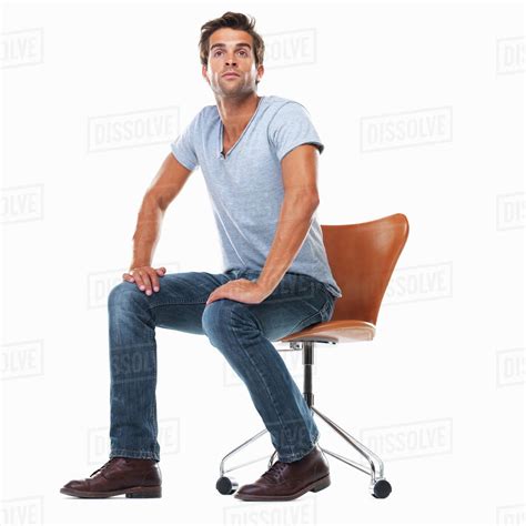 studio shot  young man sitting  chair  hands  laps stock