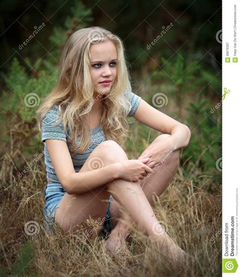 pretty blond teenager sitting in the grass stock image