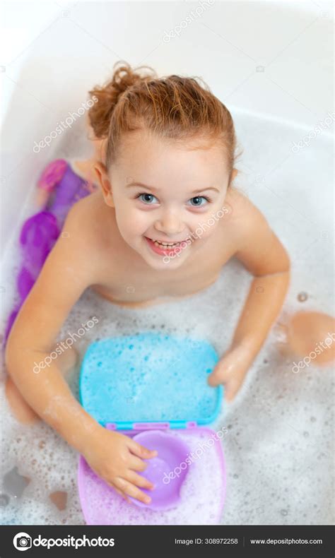 female toddler takes  bath  plays  plastic toys stock photo