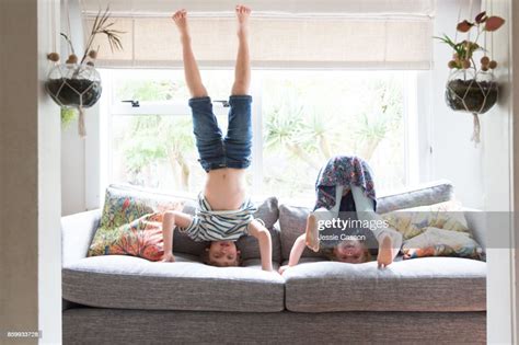 Siblings Playing On Sofa Doing Headstands Photo Getty Images