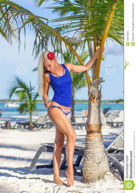 Blonde Girl At The Beach Is Posing Near Palm Tree Stock