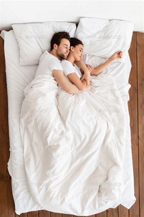 Top View Of Married Couple Sleeping Together Embracing Resting In