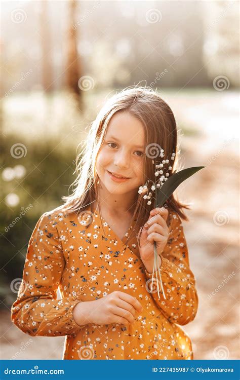 Beautiful School Age Girl With Lily Of The Valley Flowers In Her Hand