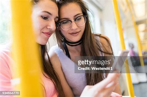 two smiling teenage girls sharing cell phone in subway high res stock