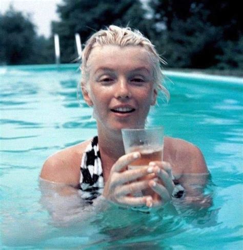 a woman in a pool holding a drink