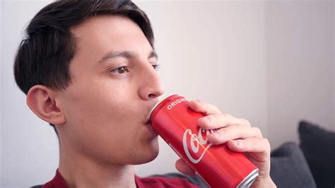 Young Man Drinks Coca Cola From A Can Sitting At Home Relaxing Stock