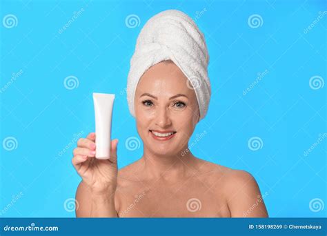 portrait of beautiful mature woman with perfect skin holding tube of