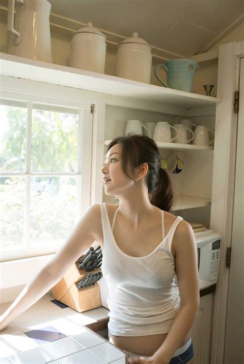 A Woman Standing In Front Of A Window With Her Hands On The Kitchen