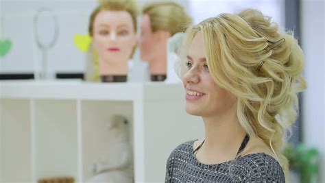 cute blonde girl admires herself in the mirror in the beauty salon close up stock footage video