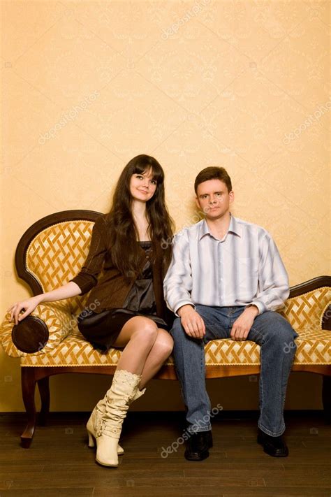 jeune belle femme et jeune homme assis sur le canapé dans la chambre