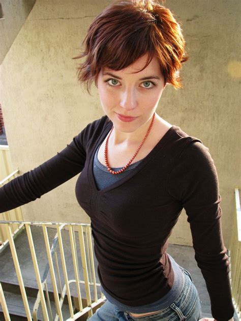 A Woman With Short Hair Standing In Front Of Stairs