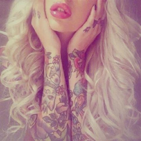 A Woman With Long Blonde Hair And Tattoos On Her Arms Is Posing For The