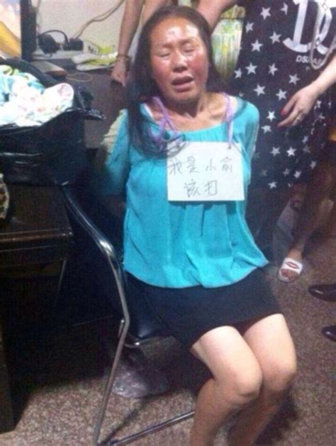 chinese shoplifter made to sit in shop window with sign