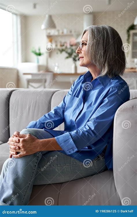 classy relaxed mature older woman relaxing sitting on couch at home