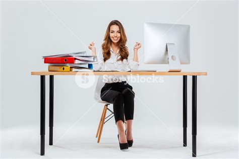 full length portrait of a cheerful woman sitting at the table in office