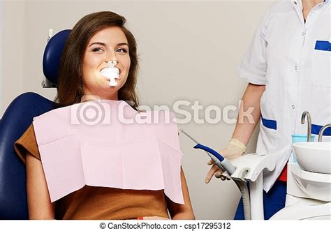 dentist making teeth whitening procedure to woman patient